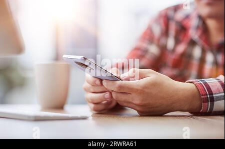 Un uomo d'affari in ufficio usa un telefono, guarda lo schermo di uno smartphone, naviga in Internet Foto Stock