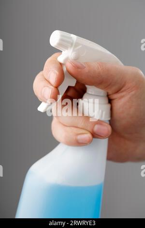 Mano che tiene una plastica flacone spray riempita con liquido di colore blu Foto Stock