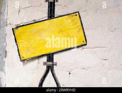 Vecchio cartello metallico vuoto appeso davanti ai cavi elettrici Foto Stock