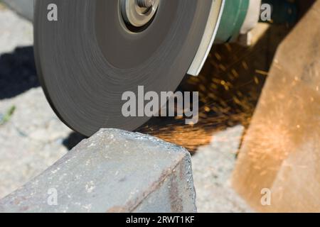 Strofinare un pezzo di ferro per mezzo di un disco abrasivo su un flex. Uomo che strofina un pezzo di metallo per mezzo di un Flex Foto Stock