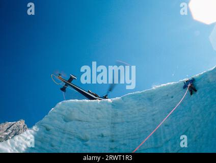 Scalatori su ghiaccio ed elicotteri sul ghiacciaio Bosson a Chamonix, Francia Foto Stock