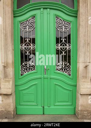 Porta in legno verde con calandra decorativa in ferro battuto bianco Foto Stock