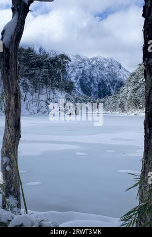 Una vista pittoresca del lago ghiacciato ai piedi di alte montagne coperte di neve Foto Stock