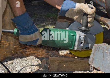 Lavorare su un pezzo di metallo per mezzo di un disco abrasivo su un flex. Uomo che strofina un pezzo di metallo per mezzo di un Flex Foto Stock