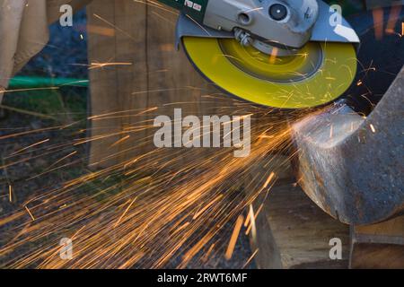 Lavorare su un pezzo di metallo per mezzo di un disco abrasivo su un flex. Uomo che strofina un pezzo di metallo per mezzo di un Flex Foto Stock