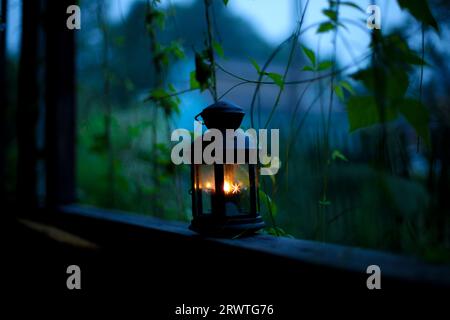 vecchia lampada con una candela all'aperto. un'antica lanterna con una candela illumina la strada di notte Foto Stock