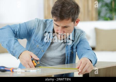 un uomo che lavora nel locale di lavoro del falegname con nastro adesivo Foto Stock