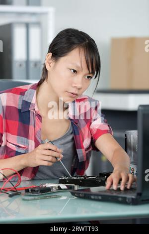 meccanico femminile che fissa un dispositivo Foto Stock