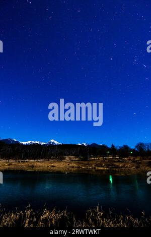 The Yatsugatake mountain range and starry sky from Lake Maruyachi in Yatsugatake Nature Park Stock Photo