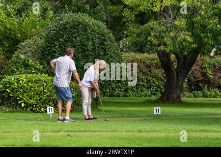 Uomo e donna di mezza età, presumibilmente una coppia, giocando a putting o a golf pazzo su un putting green in erba in estate nel Regno Unito. Foto Stock
