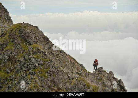 Arrampicatori che camminano lungo la cresta di Yatsugatake e il mare di nuvole Foto Stock