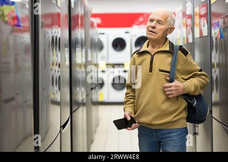 Pensionato Senor MAN che acquista un frigorifero nello showroom del negozio di elettrodomestici Foto Stock