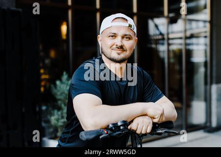 Uomo sorridente piacevole che guida un calciatore scooter. Uomo felice di guida calcio scooter Foto Stock