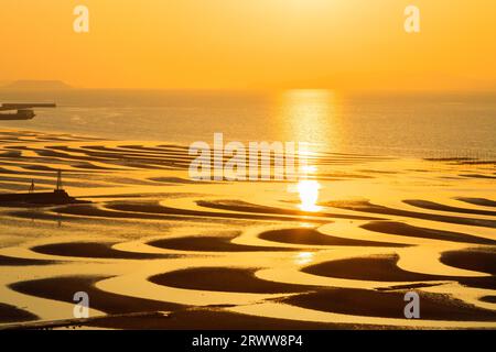 Modello di sabbia della costa di Mikoshirai, del mare e del sole che tramonta Foto Stock