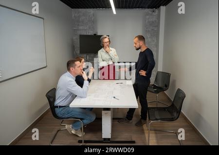L'estrusione femminile valuta il lavoro dei subordinati. Progettisti ingegneri a una riunione. Foto Stock