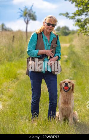 Donna che indossa un manichino e il suo obbediente Golden retriever Foto Stock