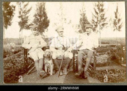 Una di una serie di cinque stampe della prigione di Nairobi, 1917. Questa immagine mostra due uomini europei in uniforme militare in piedi nel giardino di fronte a un edificio in stile europeo con scale di legno che conducono all'interno. Due cani sono stesi a terra accanto a loro. Il signor Stanton è morto pochi mesi dopo che è stata scattata questa foto. Didascalia del testo originale: S/M/ Nixon and H.A.S. [Herman Armin Stanton] didascalia della pagina originale: Nairobi Jail 1917. Foto Stock