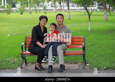 Contea di Luannan, Cina - 13 giugno 2023: La famiglia riposa su una panchina del parco, Cina settentrionale Foto Stock