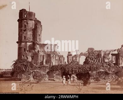 Vista delle rovine della residenza britannica, ricoperta di piante. Fu rovinato durante la ribellione indiana del 1857. Due uomini indiani si trovano davanti all'edificio sul prato. Inscribed on negative: Frith's Series. 3040 The Residency Lucknow.Caption recita: Lucknow Residency. Foto Stock