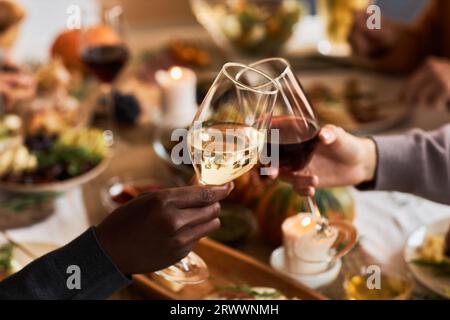 Primo piano di due persone che tengono bicchieri da vino e brindano in festa al tavolo della cena, nello spazio fotocopie Foto Stock