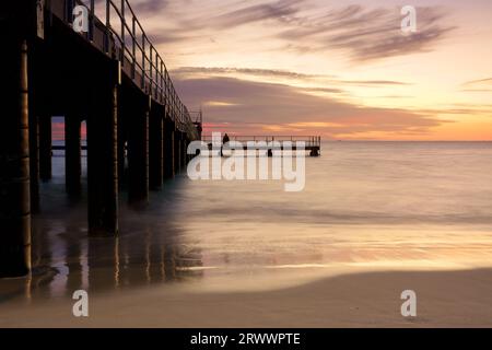 Tramonto al Coogee Beach Jetty con una persona che pesca nei sobborghi meridionali di Perth, Australia Occidentale Foto Stock