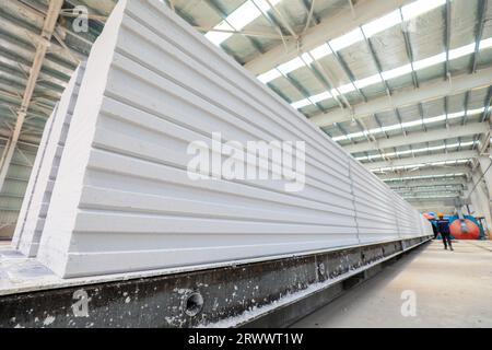 Contea di Luannan, Cina - 17 giugno 2023: I lavoratori stanno lavorando intensamente sulla linea di produzione di nuovi materiali da costruzione - pannelli divisori leggeri Foto Stock