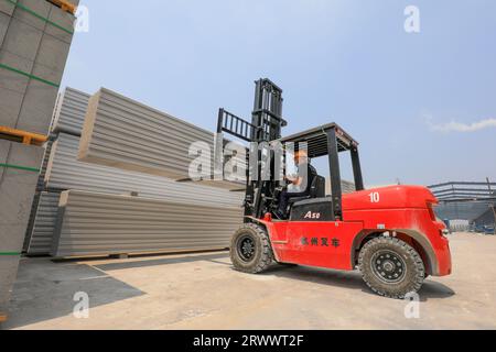 Contea di Luannan, Cina - 17 giugno 2023: I lavoratori utilizzano carrelli elevatori per trasportare nuovi materiali da costruzione in una fabbrica, nel nord della Cina Foto Stock