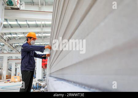 Contea di Luannan, Cina - 17 giugno 2023: I lavoratori stanno lavorando intensamente sulla linea di produzione di nuovi materiali da costruzione - pannelli divisori leggeri Foto Stock