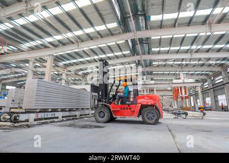 Contea di Luannan, Cina - 17 giugno 2023: I lavoratori utilizzano carrelli elevatori per trasportare nuovi materiali da costruzione in una fabbrica, nel nord della Cina Foto Stock