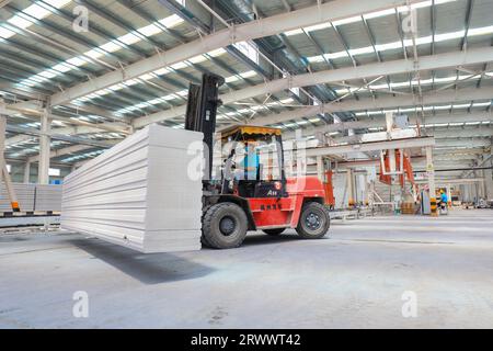 Contea di Luannan, Cina - 17 giugno 2023: I lavoratori utilizzano carrelli elevatori per trasportare nuovi materiali da costruzione in una fabbrica, nel nord della Cina Foto Stock