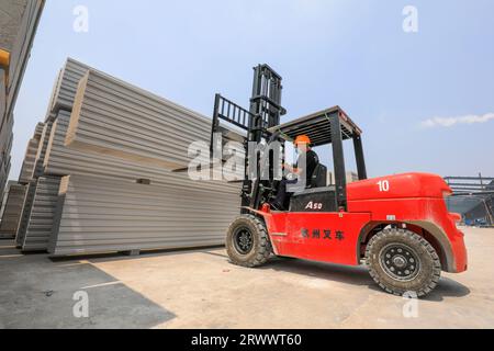 Contea di Luannan, Cina - 17 giugno 2023: I lavoratori utilizzano carrelli elevatori per trasportare nuovi materiali da costruzione in una fabbrica, nel nord della Cina Foto Stock