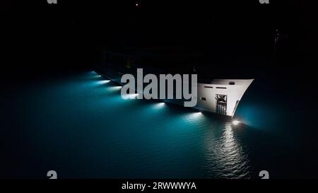 Yacht a motore di lusso, splendide luci sottomarine che illuminano le acque blu turchesi di Cavtat Bay, Croazia. Illuminazione sott'acqua Foto Stock