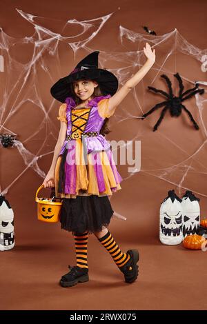 Una donna in un costume di strega in un cappello tiene una zucca secchio di  caramella e una palla. Halloween persone Foto stock - Alamy