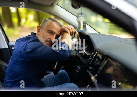 Il giovane seduto in macchina è molto turbato e stressato Foto Stock