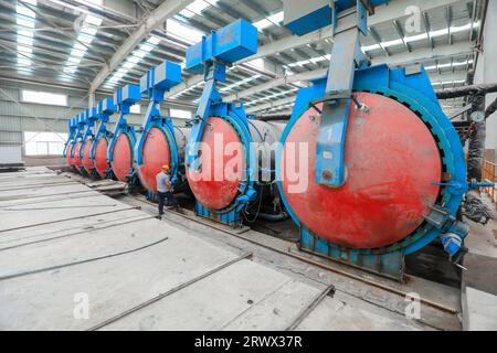 Contea di Luannan, Cina - 27 giugno 2023: I lavoratori stanno aprendo l'autoclave sulla linea di produzione di pannelli divisori leggeri in fabbrica Foto Stock