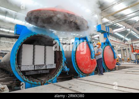 Contea di Luannan, Cina - 27 giugno 2023: I lavoratori stanno aprendo l'autoclave sulla linea di produzione di pannelli divisori leggeri in fabbrica Foto Stock