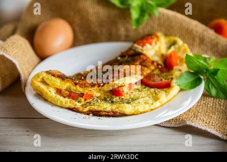 Omelette farcite con pomodori su uno sfondo di legno chiaro. Cibo salutare per la colazione. Foto Stock