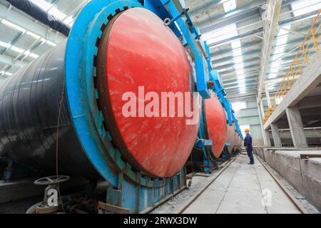 Contea di Luannan, Cina - 27 giugno 2023: I lavoratori stanno manipolando l'autoclave dei materiali da costruzione per il trasporto nella fabbrica Foto Stock