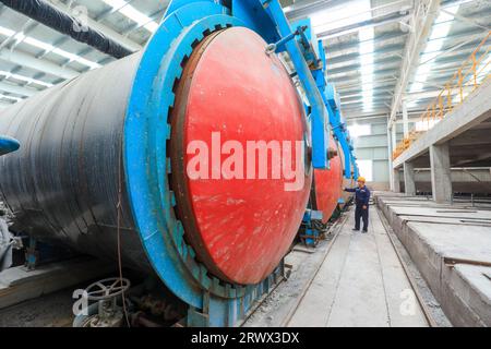 Contea di Luannan, Cina - 27 giugno 2023: I lavoratori stanno manipolando l'autoclave dei materiali da costruzione per il trasporto nella fabbrica Foto Stock
