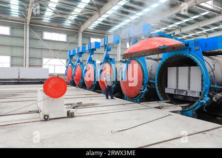 Contea di Luannan, Cina - 27 giugno 2023: I lavoratori stanno manipolando l'autoclave dei materiali da costruzione per il trasporto nella fabbrica Foto Stock