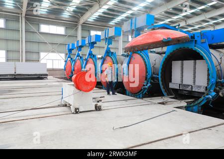Contea di Luannan, Cina - 27 giugno 2023: I lavoratori stanno manipolando l'autoclave dei materiali da costruzione per il trasporto nella fabbrica Foto Stock