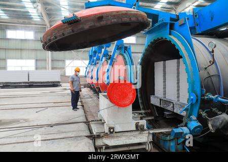 Contea di Luannan, Cina - 27 giugno 2023: I lavoratori stanno manipolando l'autoclave dei materiali da costruzione per il trasporto nella fabbrica Foto Stock