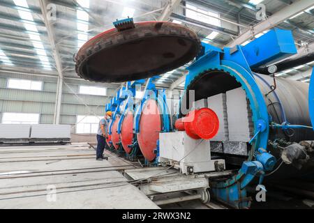 Contea di Luannan, Cina - 27 giugno 2023: I lavoratori stanno manipolando l'autoclave dei materiali da costruzione per il trasporto nella fabbrica Foto Stock