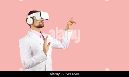 Uomo con un innovativo visore VR che sperimenta la realtà virtuale e tocca oggetti virtuali Foto Stock