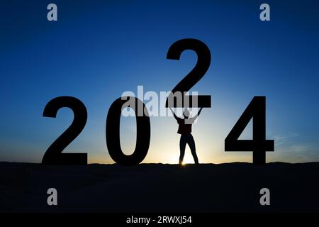 2024, silhouette di una donna in piedi all'alba, biglietto d'auguri per il nuovo anno Foto Stock