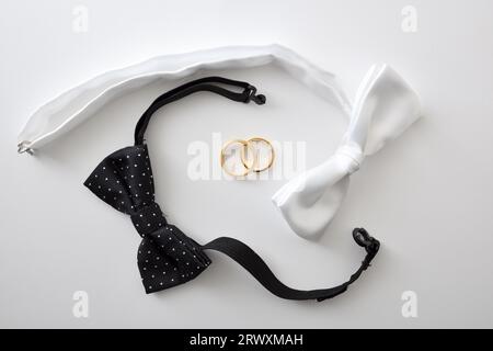 Sfondo concettuale per matrimoni gay con fiocco bianco e nero che circonda anelli nuziali. Vista dall'alto. Foto Stock