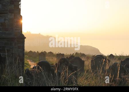 Tramonto sul cimitero della storica St Mary's Church, sulla scogliera orientale ventilata dall'abbazia di Whitby nel North Yorkshire, Regno Unito Foto Stock