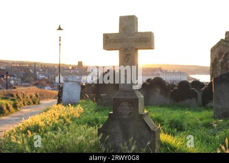 Tramonto sul cimitero della storica St Mary's Church, sulla scogliera orientale ventilata dall'abbazia di Whitby nel North Yorkshire, Regno Unito Foto Stock