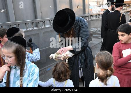 Gerusalemme, Israele. 21 settembre 2023. Un ebreo ultra-ortodosso mostra un pollo ai bambini che sarà usato nell'antico rituale Kapparot a Mea Shearim a Gerusalemme, giovedì 21 settembre 2023. Il Kapparot è preformato prima dello Yom Kippur, il giorno dell'Espiazione, il giorno più sacro del calendario ebraico, e trasferisce simbolicamente i peccati dell'anno passato al pollo. Foto di Debbie Hill/ Credit: UPI/Alamy Live News Foto Stock