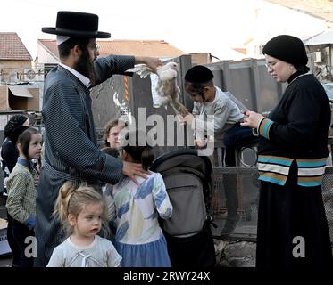 Gerusalemme, Israele. 21 settembre 2023. Un ebreo ultra-ortodosso alza un pollo sulla testa dei suoi figli durante l'antico rituale Kapparot a Mea Shearim a Gerusalemme, giovedì 21 settembre 2023. Il Kapparot è preformato prima dello Yom Kippur, il giorno dell'Espiazione, il giorno più sacro del calendario ebraico, e trasferisce simbolicamente i peccati dell'anno passato al pollo. Foto di Debbie Hill/ Credit: UPI/Alamy Live News Foto Stock